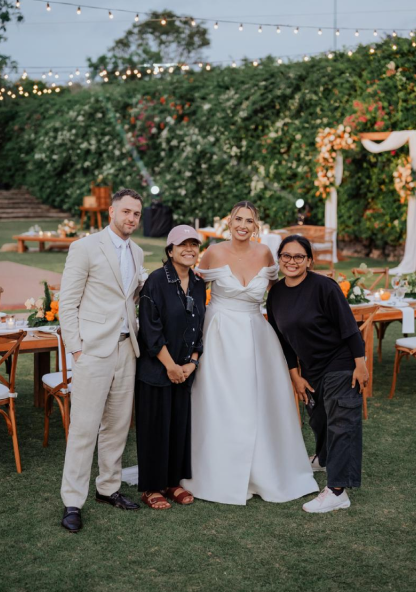 A newlywed couple posing with two members of The About Wedding team