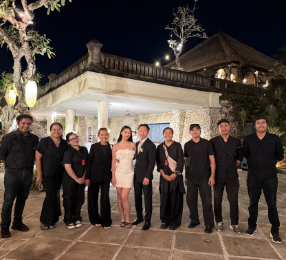 A newlywed couple posing with their wedding crew at night