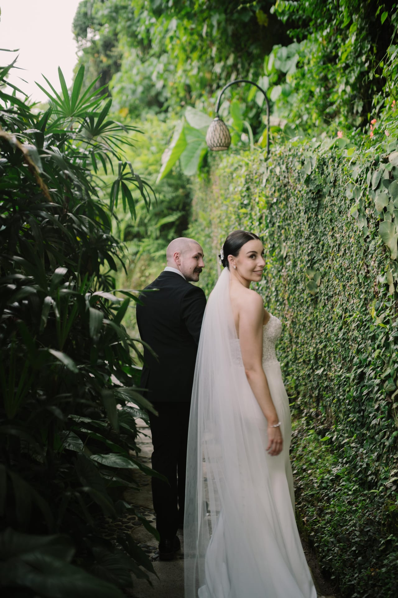 Newlyweds looking back along a lush tropical path in Bali